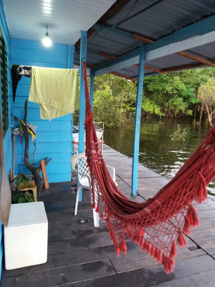 Un'amaca rossa sulla veranda di una casa di legno sul fiume