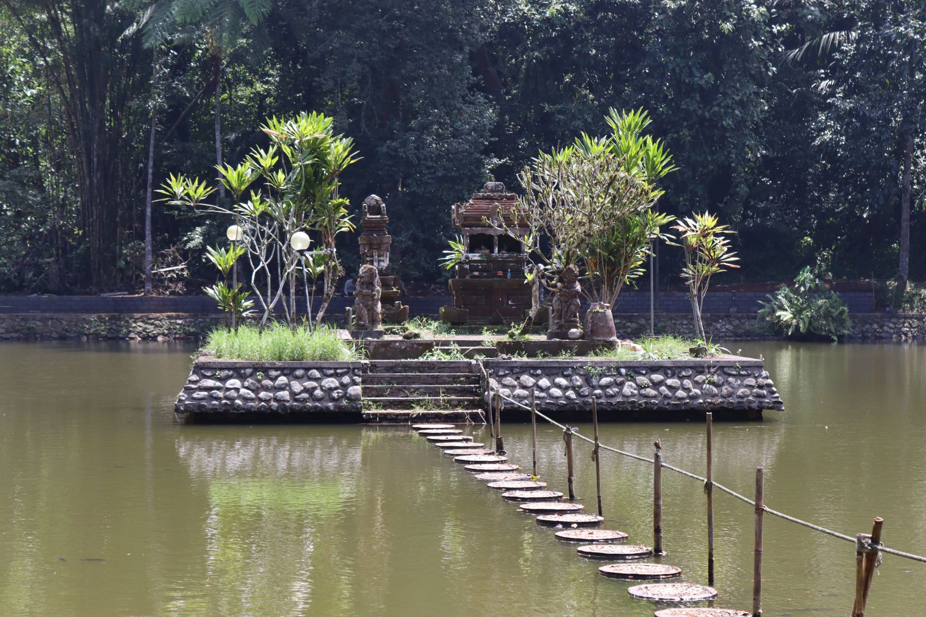 Passerella di pietre sull’acqua conduce a un piccolo santuario balinese.