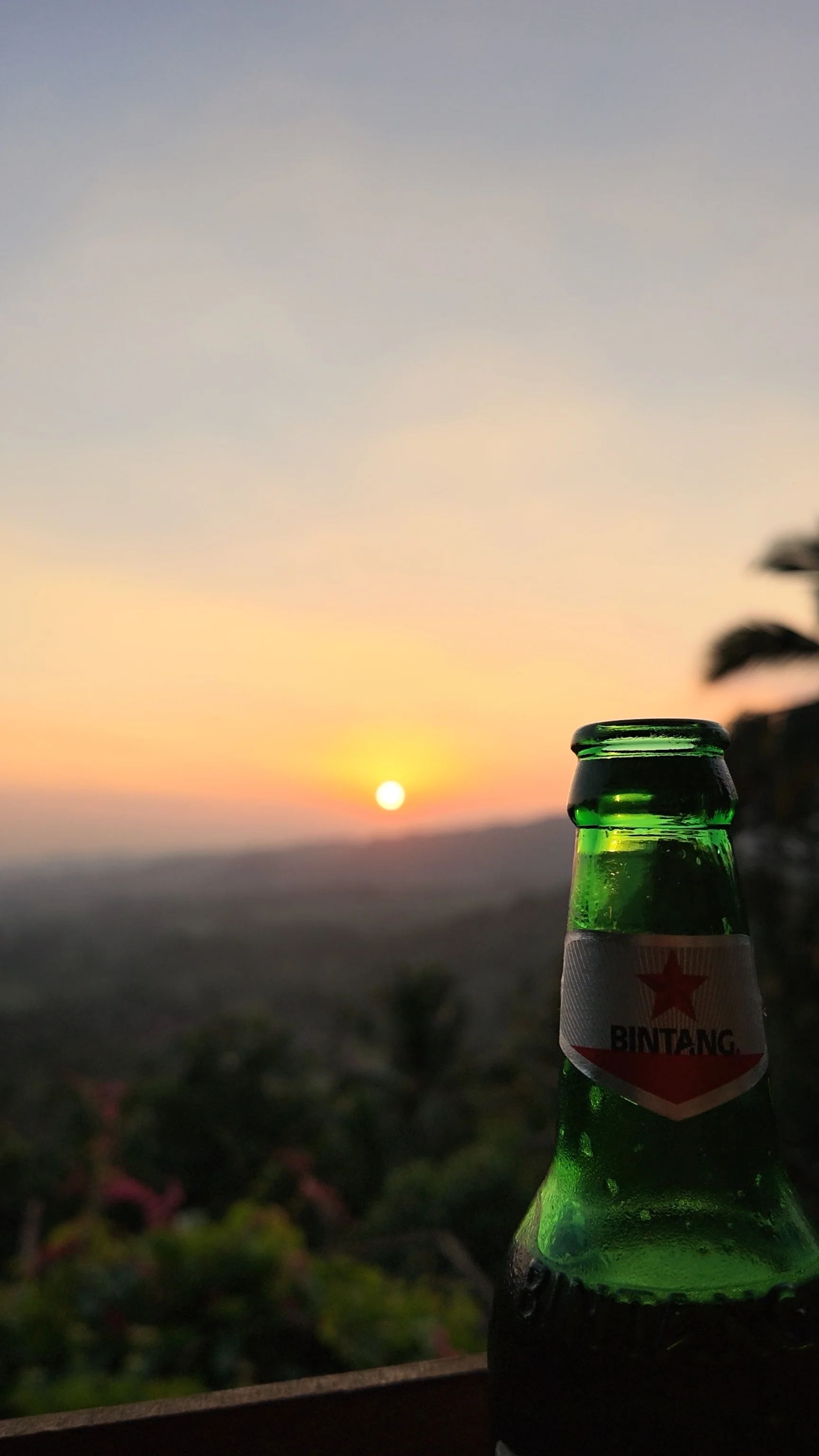 Birra davanti al paesaggio al tramonto presso le cascate di Gembleng.
