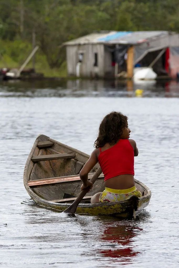 Una ragazza spinge una canoa nel fiume davanti a una casa sull'acqua