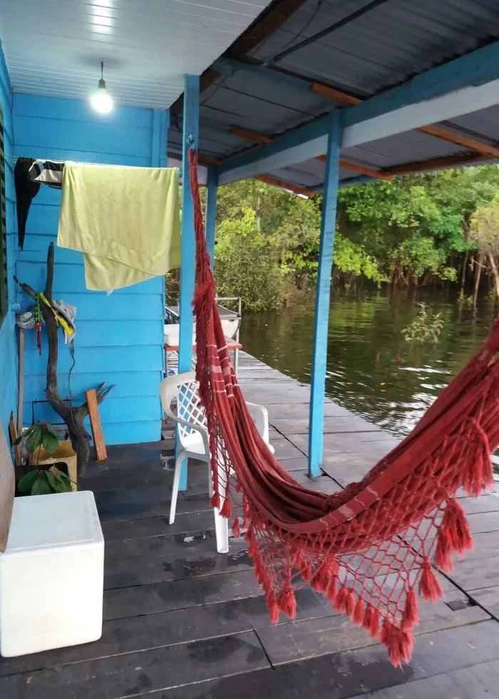 Un'amaca rossa sulla veranda di una casa di legno sul fiume